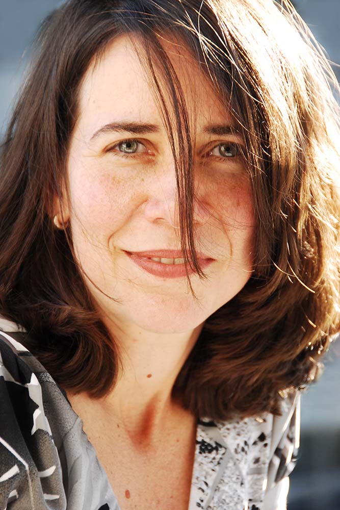 Photographic portrait of Andrea with wavy brown hair.