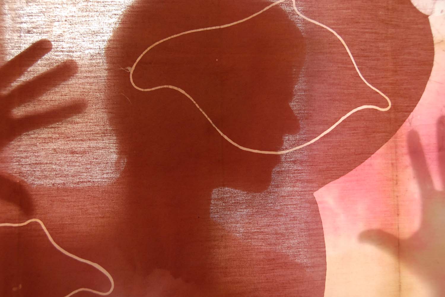 Portrait of Fernanda Vargas behind one of her batik works.