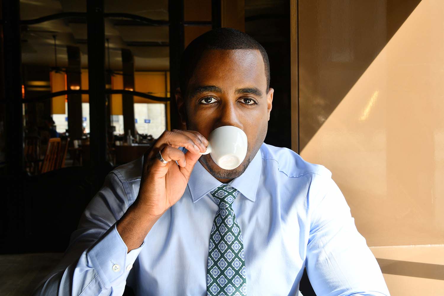 Portrait photo d'un homme de face en train de boire un café.