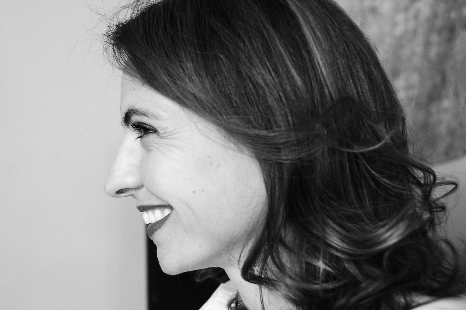Black and white photographic portrait of a woman in profile, with wavy hair.